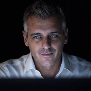Massimo Rosi illuminato dalla luce dello schermo